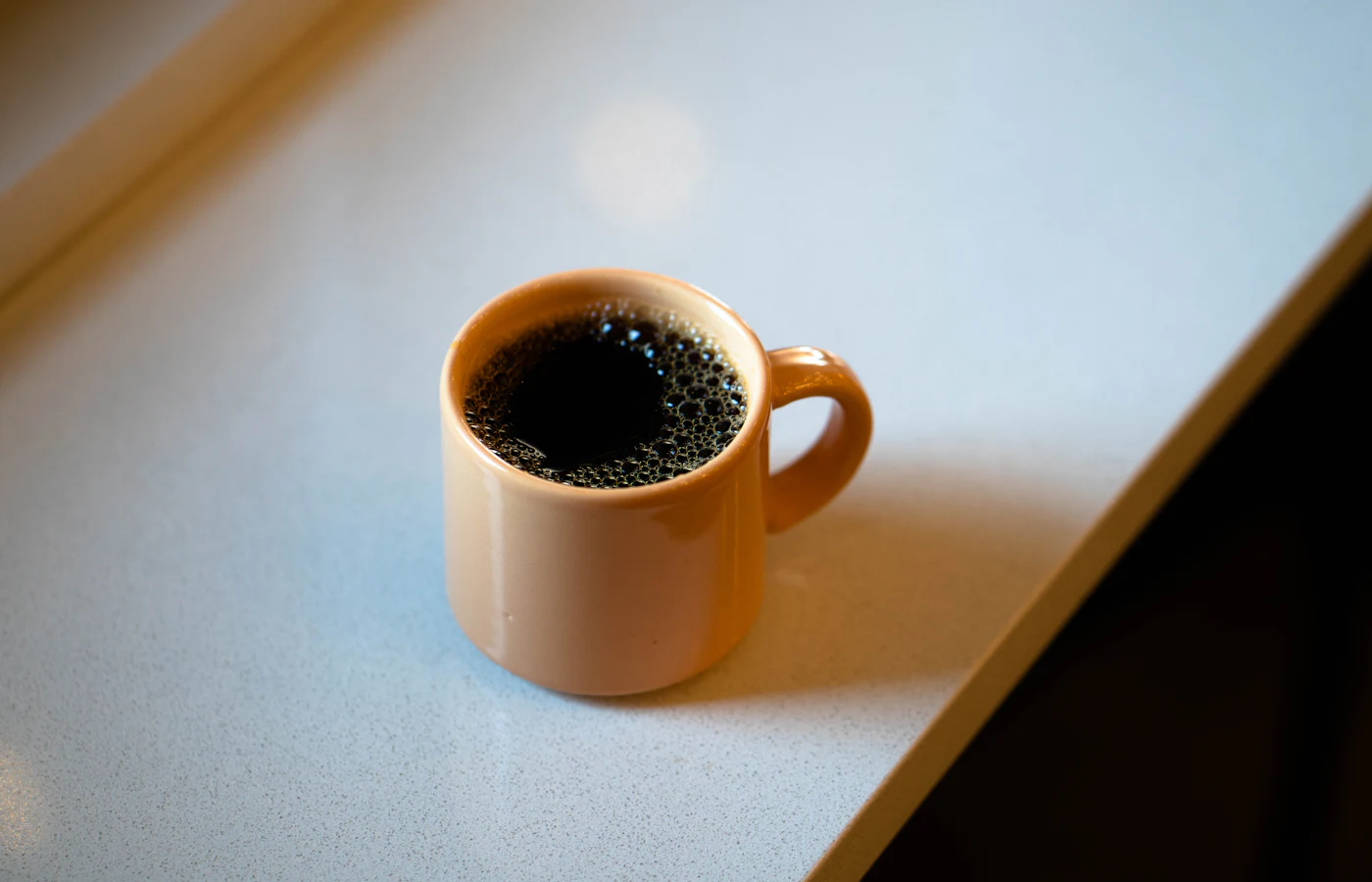 Eine Tasse schwarzer Kaffee auf einem hellen Tisch
